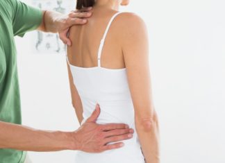 Physiotherapeuten untersucht Frau mit Rückenproblemen